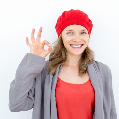 Estudiante con gorro fránces, saludando y diciendo ok