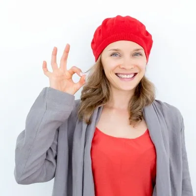 Estudiante con gorro francés, saludando y diciendo "ok"